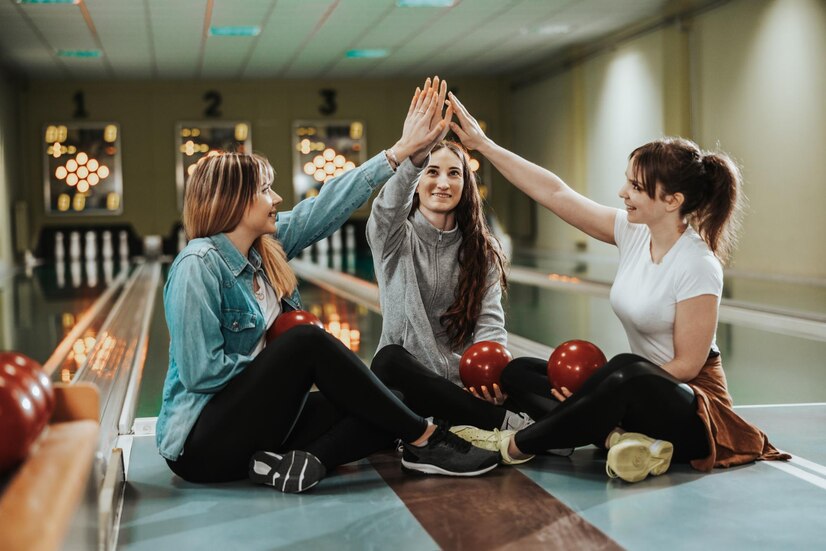 three cheerful girls giving high five while sitting lane with bowling ball preparing throwing bowling club 360066 22778